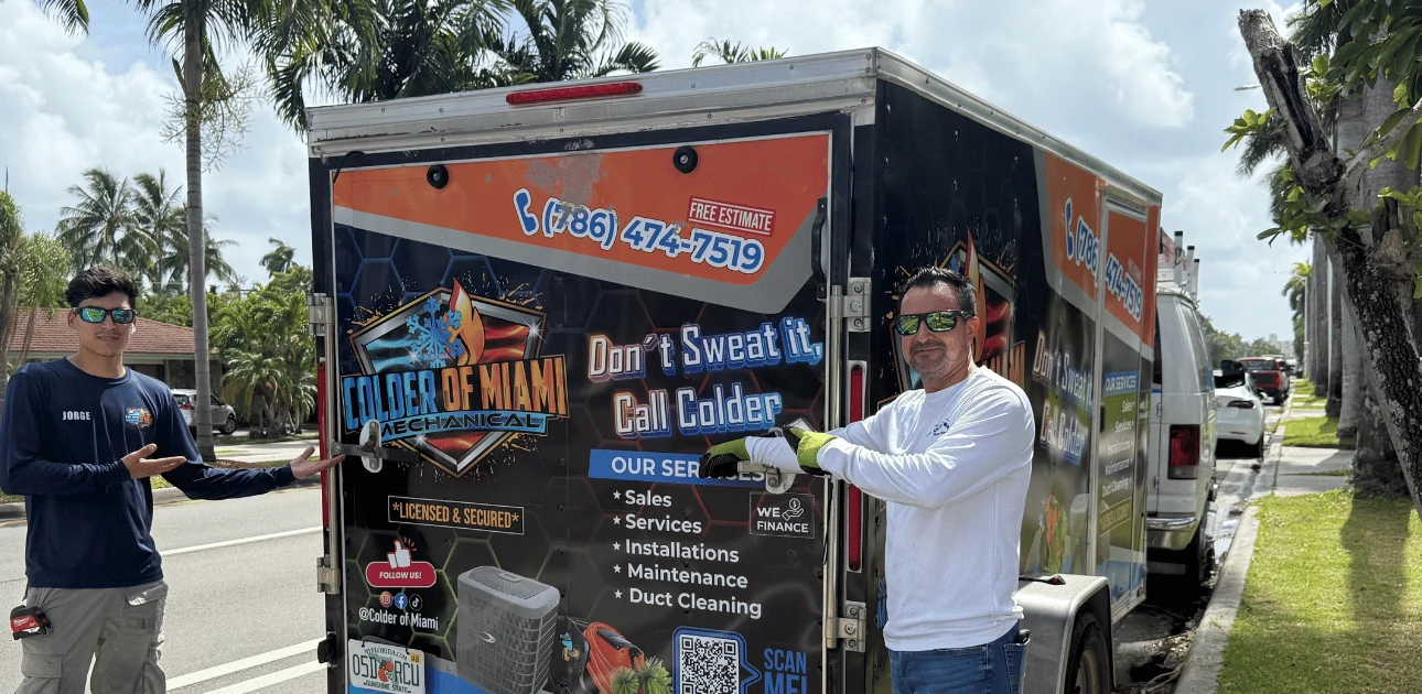 Yadiel Castro and a technician from Colder of Miami Inc showcasing their branded HVAC trailer in South Florida. Includes contact info, financing options, and strong company branding.