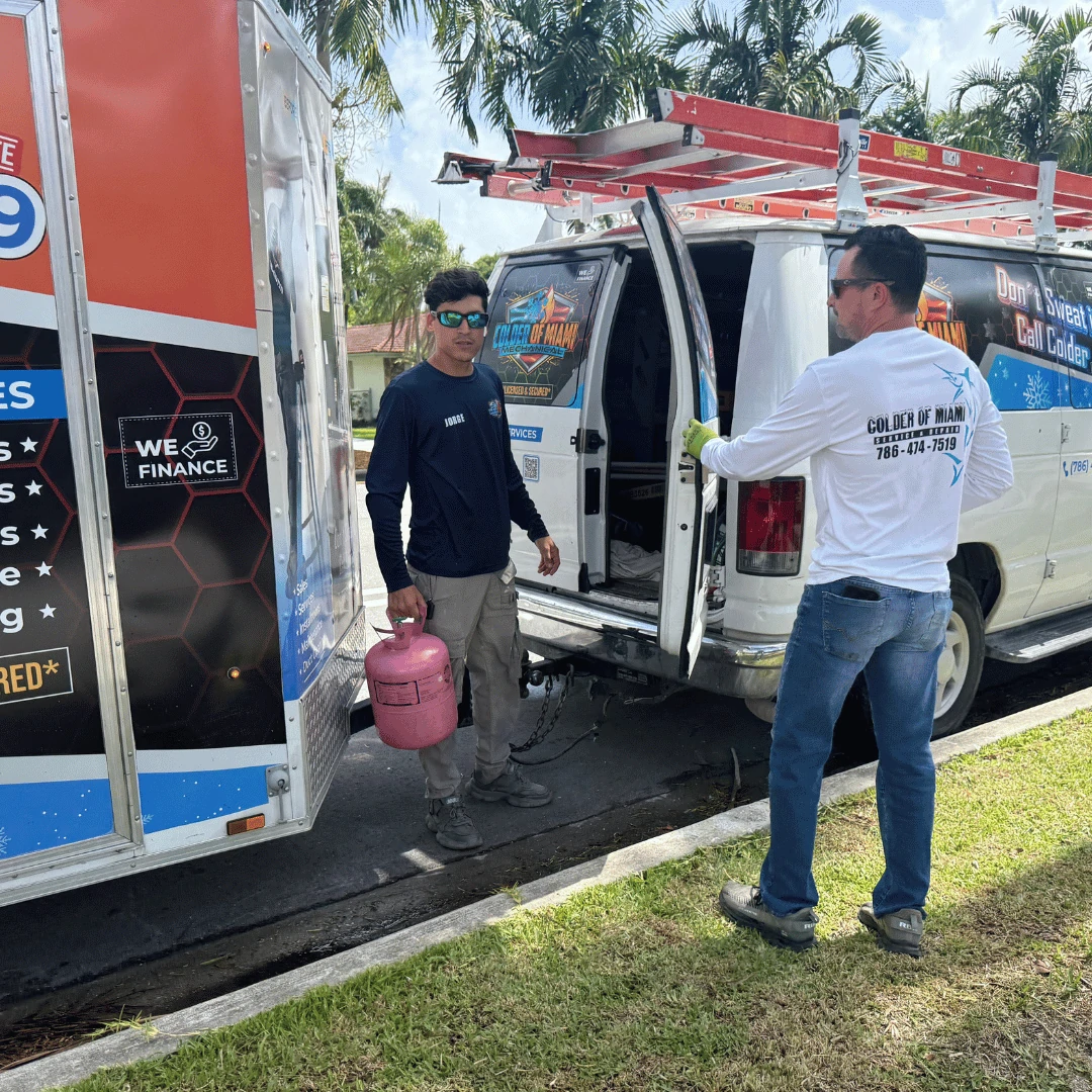 Yadiel Castro and a technician from Colder of Miami Inc showcasing their branded HVAC trailer in South Florida. Includes contact info, financing options, and strong company branding.