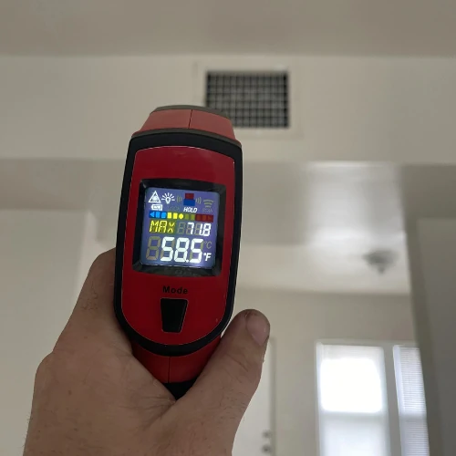 Infrared thermometer reading 58.5°F at an air vent during an AC repair service in Fort Lauderdale.